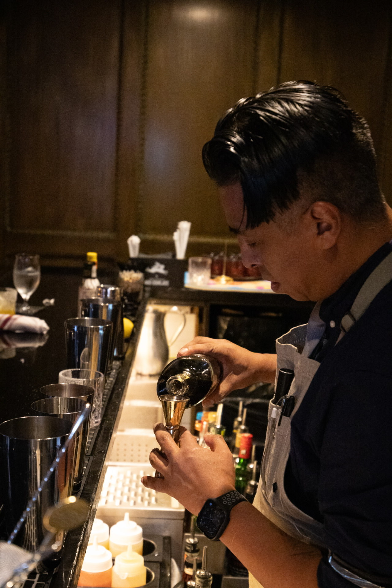 A Bueno bartender measuring spirits behind the bar