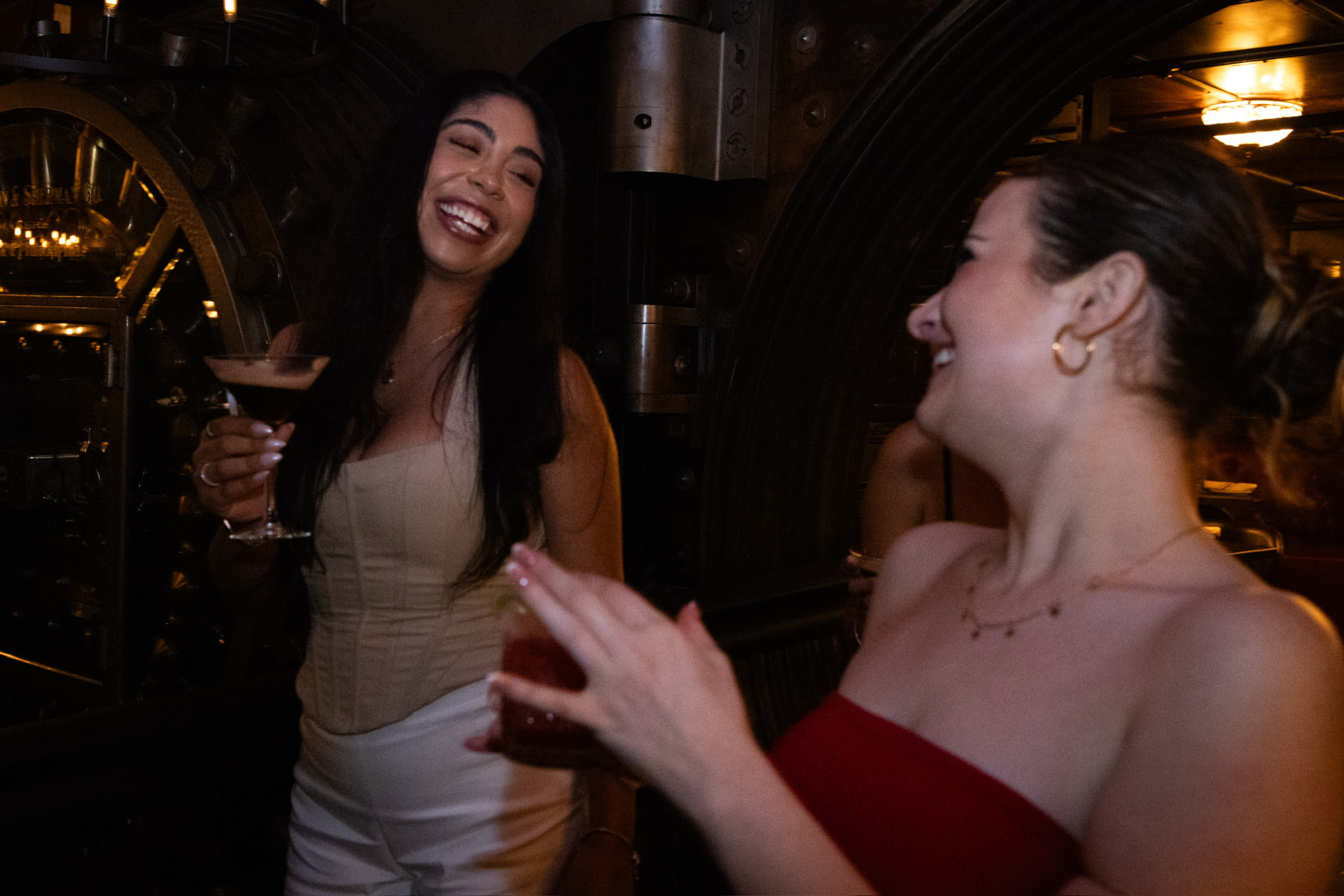 Guests sharing cocktails beside the bank vault at Bueno